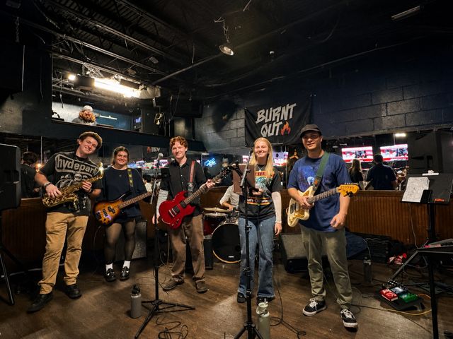 A five-piece band playing on the stage at The Woods.